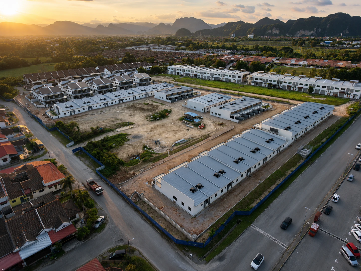 Sunset aerial of Taman Lapangan Irama construction site — mix of completed and in-progress homes, with the Kinta Valley karst range in the distance